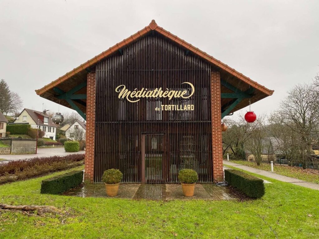 Lettres découpées dorées « Médiathèque du Tortillard » posées sur la façade en claire-voie bois d'un bâtiment public, enseigne réalisée par Refletscom